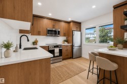Wood-finish cabinetry with black hardware, white countertops, stainless steel appliances, white subway tile backsplash, and wood-finish flooring - 