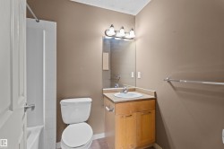 Bathroom featuring a light wood-finish vanity with an integrated sink, a rectangular mirror, and a three-light fixture - 