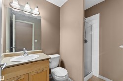 Bathroom featuring a light wood-finish vanity with an integrated sink, polished chrome faucet, and overhead three-bulb vanity light - 