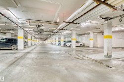 Underground parking garage featuring concrete flooring, exposed overhead piping, and fluorescent lighting - 
