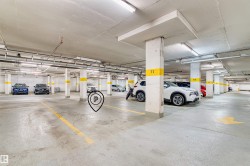 Underground parking garage featuring concrete flooring, structural support columns, overhead lighting, and painted parking space indicators - 