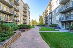 Landscaped courtyard featuring a stamped concrete pathway, manicured lawns, and brick-faced retaining walls with mature shrubbery - 