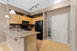 Functional kitchen featuring light wood cabinetry, laminate countertops, a stainless steel sink, and black appliances - 