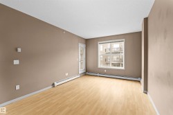 Spacious living area featuring light wood-finish flooring, a neutral wall palette, and white baseboard heaters - 