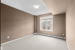 Room featuring neutral-toned walls, light-colored carpeting, and a large window with blinds - 
