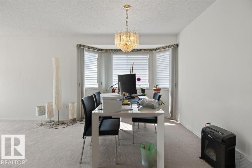 Recessed bay window with multiple vertical blinds, complemented by a gold-toned chandelier - 1046 Jones Crescent Nw, Edmonton, AB - Indoor Photo Showing Office