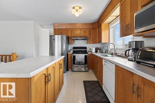 Kitchen featuring wood cabinetry, white countertops, stainless steel appliances, and tile flooring - 1046 Jones Crescent Nw, Edmonton, AB - Indoor Photo Showing Kitchen