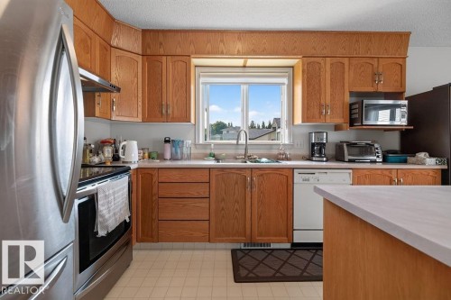 Kitchen featuring light wood cabinetry, a stainless steel refrigerator, and a built-in dishwasher - 1046 Jones Crescent Nw, Edmonton, AB - Indoor Photo Showing Kitchen With Double Sink