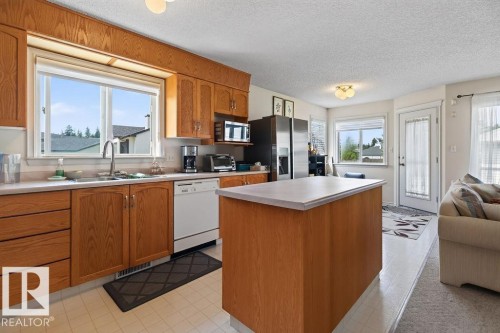 Kitchen featuring wood cabinetry, a center island with a laminate countertop, and a double basin sink - 1046 Jones Crescent Nw, Edmonton, AB - Indoor Photo Showing Kitchen With Double Sink