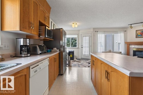 Kitchen featuring light wood cabinetry, white countertops, a built-in stainless steel microwave, and a white dishwasher - 1046 Jones Crescent Nw, Edmonton, AB - Indoor Photo Showing Kitchen