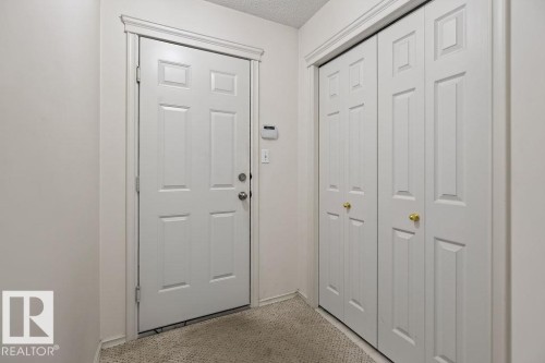 Entryway featuring a white paneled door, coordinating trim, and textured carpet flooring - 1046 Jones Crescent Nw, Edmonton, AB - Indoor Photo Showing Other Room