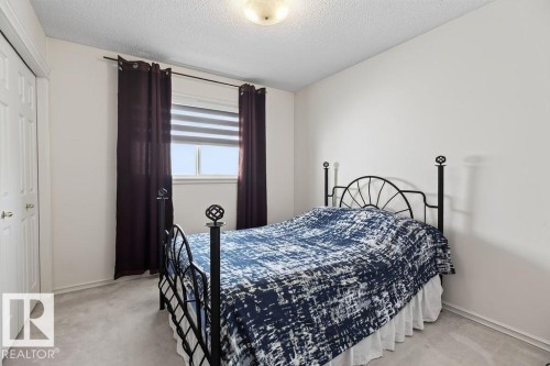 Bedroom featuring light neutral wall paint, light gray carpet flooring, and a window with blinds and dark-colored curtains - 1046 Jones Crescent Nw, Edmonton, AB - Indoor Photo Showing Bedroom