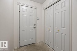 Entryway featuring a white paneled door, coordinating trim, and textured carpet flooring - 
