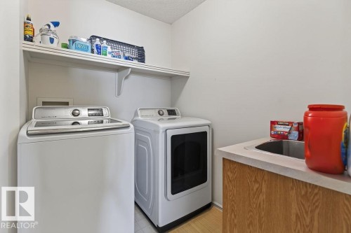 Dedicated laundry room featuring a utility sink with a laminate countertop, wood-finish cabinetry, and an overhead storage shelf - 1046 Jones Crescent Nw, Edmonton, AB - Indoor Photo Showing Laundry Room