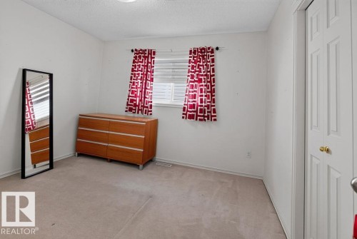 Bright bedroom space featuring a window with horizontal blinds and an overhead flush-mount light fixture - 1046 Jones Crescent Nw, Edmonton, AB - Indoor