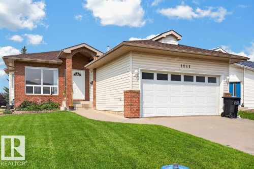 Exterior featuring a brick and siding facade, a two-car garage with transom windows, a concrete driveway, a front entry with an arched portico, and a landscaped lawn - 1046 Jones Crescent Nw, Edmonton, AB - Outdoor
