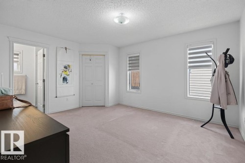 Bright room featuring two windows with horizontal blinds, a neutral carpeted floor, and a bi-fold closet door - 1046 Jones Crescent Nw, Edmonton, AB - Indoor Photo Showing Other Room