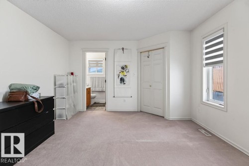Carpeted room with a double-door closet, a window with a roller shade, and access to a bathroom featuring a vanity - 1046 Jones Crescent Nw, Edmonton, AB - Indoor