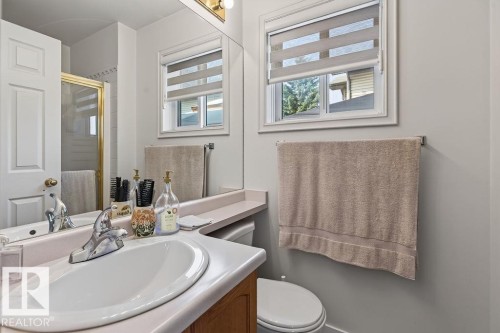 Bathroom featuring a single vanity with an integrated sink, chrome faucet, wood-finish cabinetry, and a large wall-mounted mirror - 1046 Jones Crescent Nw, Edmonton, AB - Indoor Photo Showing Bathroom