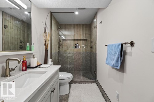 Contemporary bathroom featuring a spacious glass-enclosed shower with contrasting tile work, a single vanity with an undermount sink and brushed nickel faucet, a large mirror, and recessed lighting - 1046 Jones Crescent Nw, Edmonton, AB - Indoor Photo Showing Bathroom