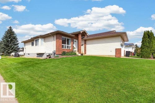 Exterior featuring brick and siding finishes, an attached garage, a mature conifer, and a front lawn - 1046 Jones Crescent Nw, Edmonton, AB - Outdoor