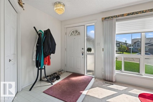 Bright entryway featuring a white paneled door with an arched glass insert, a full-length sidelight, and a large multi-pane window - 1046 Jones Crescent Nw, Edmonton, AB - Indoor