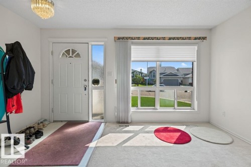 Entryway featuring a white paneled door with an arched decorative window, an adjacent sidelight, and a multi-pane window with a pleated shade - 1046 Jones Crescent Nw, Edmonton, AB - Indoor