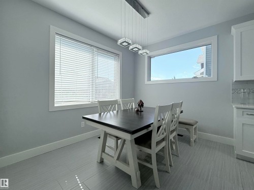 Dining area featuring light gray walls, a linear chandelier with square crystal accents, and two distinct windows - 8719 218 Street Nw, Edmonton, AB - Indoor Photo Showing Dining Room
