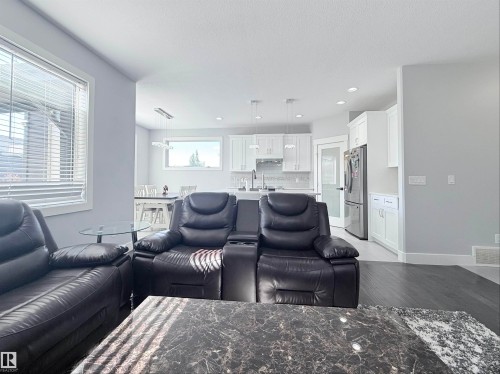 Open-concept living area featuring dark wood-finish flooring, white trim, and a clear sightline into the kitchen - 8719 218 Street Nw, Edmonton, AB - Indoor Photo Showing Living Room