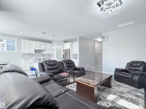 Open-concept living space featuring a modern kitchen with white cabinetry and stainless steel appliances - 8719 218 Street Nw, Edmonton, AB - Indoor Photo Showing Living Room