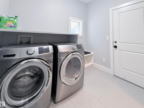 Dedicated laundry room featuring light gray walls, built-in shelving, white baseboards, and a white interior door - 8719 218 Street Nw, Edmonton, AB - Indoor Photo Showing Laundry Room