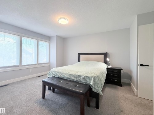 Bedroom with light gray carpeting, multiple windows with blinds, and white baseboards - 8719 218 Street Nw, Edmonton, AB - Indoor Photo Showing Bedroom