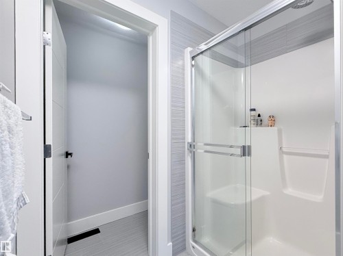 Enclosed shower with a clear glass sliding door, integrated seating, and built-in shelving - 8719 218 Street Nw, Edmonton, AB - Indoor Photo Showing Bathroom