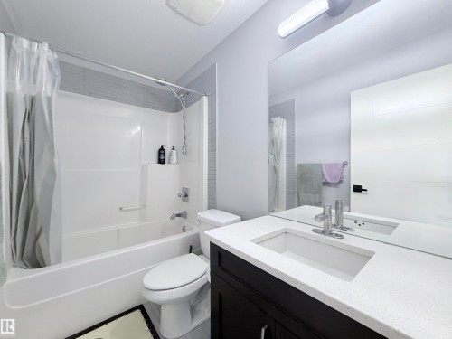 Bathroom featuring a single vanity with a white countertop, an undermount sink, and a large wall-mounted mirror - 8719 218 Street Nw, Edmonton, AB - Indoor Photo Showing Bathroom
