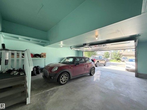 Spacious garage featuring a concrete floor, light blue painted walls, an open garage door, and built-in shelving - 8719 218 Street Nw, Edmonton, AB - Indoor Photo Showing Garage