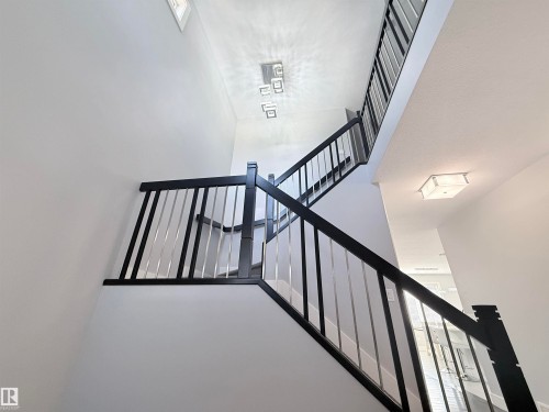 Two-story staircase featuring contemporary dark wood handrails with metal balusters - 8719 218 Street Nw, Edmonton, AB - Indoor Photo Showing Other Room