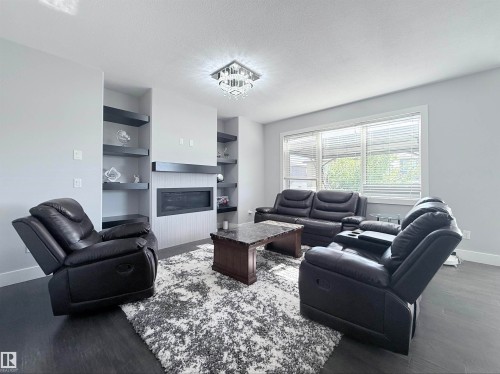 Living area featuring a wall-mounted linear fireplace with a white shiplap-style surround and dark mantel - 8719 218 Street Nw, Edmonton, AB - Indoor Photo Showing Living Room With Fireplace