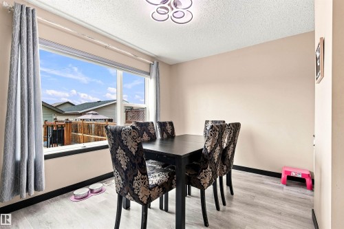 Large window offering ample natural light, light gray wood-finish flooring, and a contemporary ceiling fixture - 204 59 Street Sw, Edmonton, AB - Indoor Photo Showing Dining Room