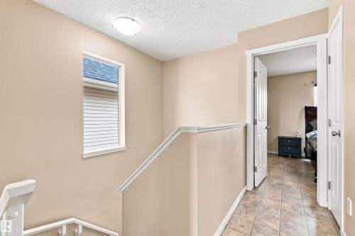 Neutral tone wall paint, textured ceiling, white trim, window with blinds, and tile flooring - 204 59 Street Sw, Edmonton, AB - Indoor Photo Showing Other Room