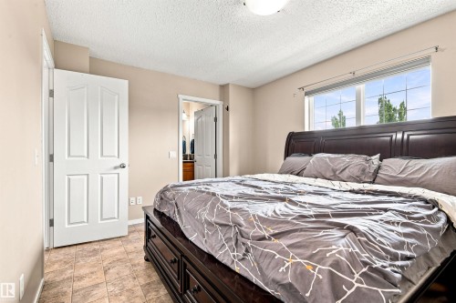 Light beige wall paint, ceiling-mounted light fixture, white interior doors, and tile flooring - 204 59 Street Sw, Edmonton, AB - Indoor Photo Showing Bedroom