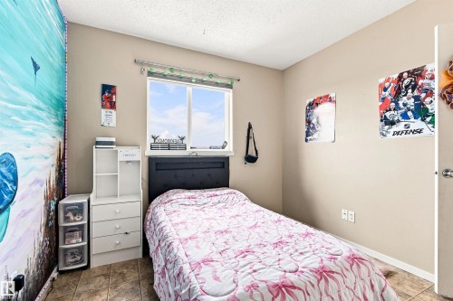 Bright bedroom featuring a large window with natural light, wood-finish flooring, neutral wall finishes, and built-in storage cabinetry - 204 59 Street Sw, Edmonton, AB - Indoor Photo Showing Bedroom