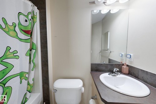 Bathroom featuring a vanity with an integrated sink, wall-mounted mirror, and a toilet - 204 59 Street Sw, Edmonton, AB - Indoor Photo Showing Bathroom