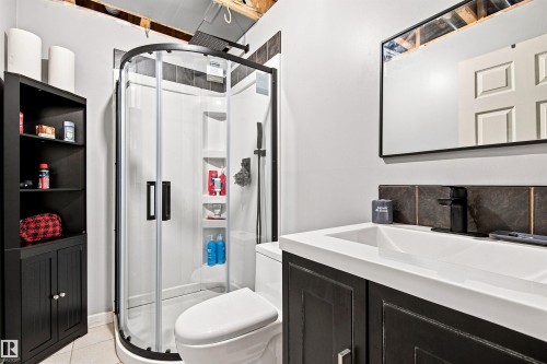 Modern primary bathroom featuring a curved glass-enclosed shower with matte black hardware, dual-sink vanity with white quartz countertop, and dark cabinetry - 204 59 Street Sw, Edmonton, AB - Indoor Photo Showing Bathroom