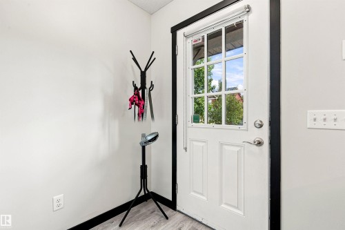 White paneled entry door with windowpanes, dark trim, and light wood-finish flooring - 204 59 Street Sw, Edmonton, AB - Indoor Photo Showing Other Room