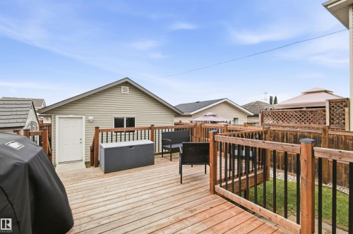 Expansive wooden deck with coordinating railings, featuring a detached garage with vinyl siding and a gable roof - 204 59 Street Sw, Edmonton, AB - Outdoor With Deck Patio Veranda With Exterior