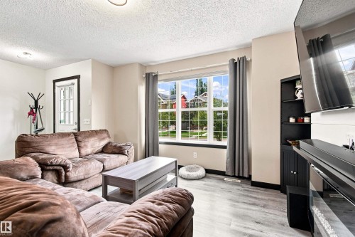Wood-finish flooring throughout, large window with ample natural light, built-in shelving, and a prominent front entry door - 204 59 Street Sw, Edmonton, AB - Indoor Photo Showing Living Room