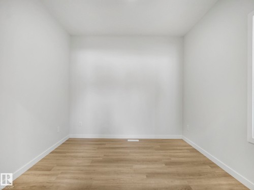 Neutral white walls with crisp white trim, wood-finish flooring, and a single window providing natural light - 239 Kinglet Boulevard Nw, Edmonton, AB - Indoor Photo Showing Other Room