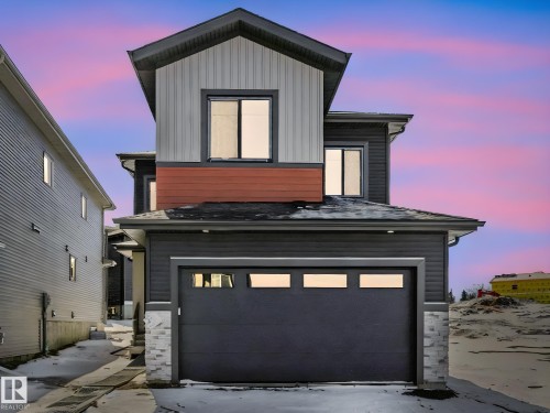 Contemporary two-story exterior featuring dark siding, light vertical siding accents, and a distinctive red horizontal panel - 239 Kinglet Boulevard Nw, Edmonton, AB - Outdoor