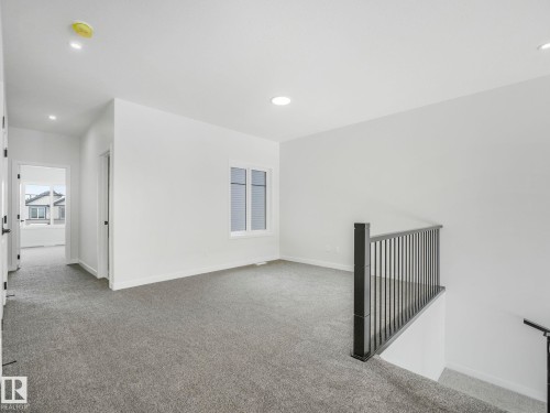 Carpeted open loft area featuring a window with horizontal blinds, recessed lighting, and a dark iron baluster railing - 239 Kinglet Boulevard Nw, Edmonton, AB - Indoor Photo Showing Other Room
