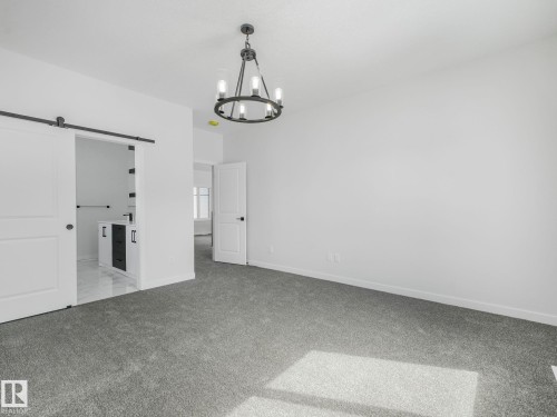 Spacious room featuring gray carpet flooring and a black metal chandelier - 239 Kinglet Boulevard Nw, Edmonton, AB - Indoor Photo Showing Other Room